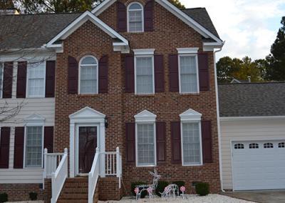 A brick house with a newly shingled roof by Housetop Roofing & Home Improvement in Raleigh, NC