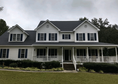 A white home with new roofing in Raleigh , NC by Housetop Roofing & Home Improvements