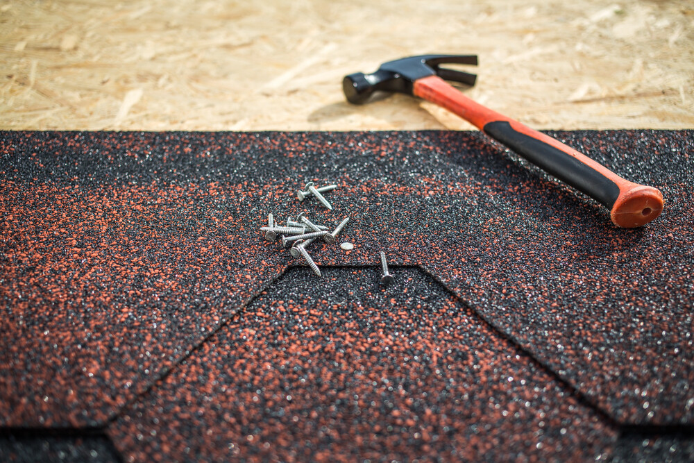 A picture of a hammer, asphalt shingles and nails