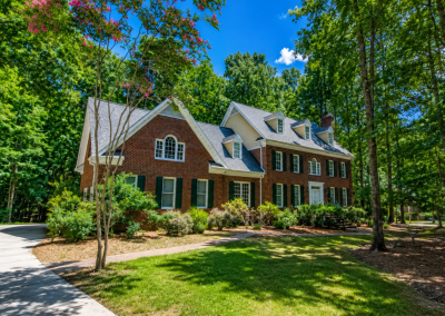 Large brick colonial home with multiple dormers and a new gray architectural shingle roof.