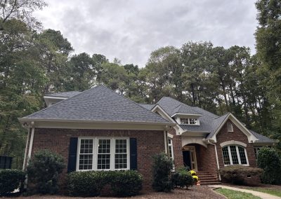 Brick home with arched windows and a new charcoal architectural shingle hip roof.