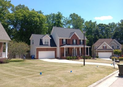 Brick two-story home with a bonus room and a new gray shingle roof on a cul-de-sac.