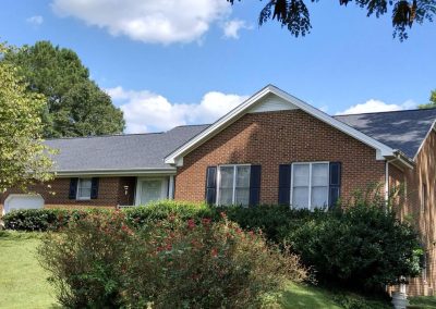 Brick ranch home with black shutters and a new dark gray architectural shingle roof.