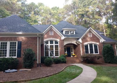 Brick ranch home with an arched dormer and a new slate gray architectural shingle roof.