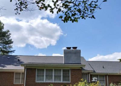 Brick ranch home with a large chimney and a new dark shingle roof.
