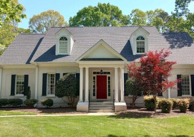 White Cape Cod home with two dormers, a red front door, and a new gray architectural shingle roof.