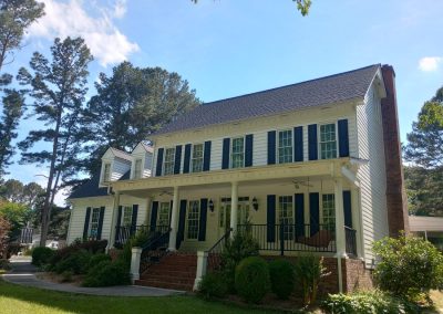 White two-story colonial with a full front porch and a new dark architectural shingle roof.