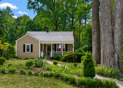 Small tan cottage with a covered front porch and a new light gray shingle roof.