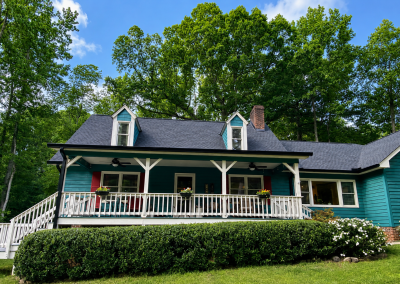 Teal farmhouse-style home with two dormers, a wide front porch, and a new charcoal shingle roof.