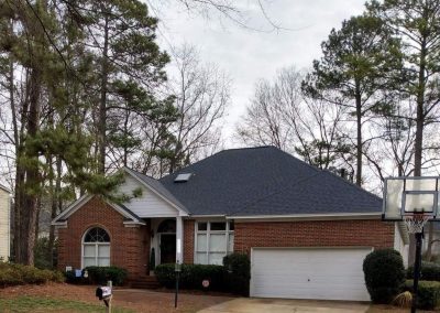Brick home in Raleigh, NC with a new dark architectural shingle hip roof and skylight.