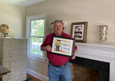 Housetop Roofing representative holding a framed Best Roofing and Gutters winner award plaque.