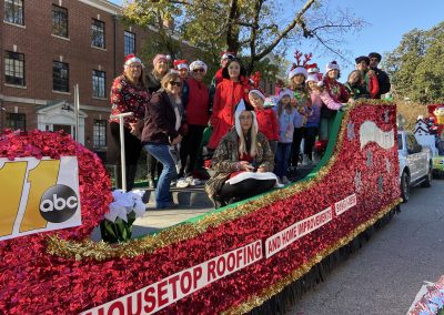 Housetop Roofing & Home Improvements red sleigh float with team members at the ABC11 Raleigh Christmas Parade.
