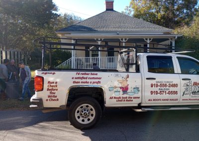 Housetop Roofing truck with Wake Forest and Raleigh phone numbers parked by a home with a new hip roof.