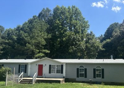 Manufactured home with a red front door and a new light gray shingle roof.
