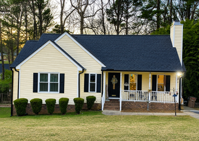 Yellow ranch home with a chimney, front porch, and a new black architectural shingle roof.