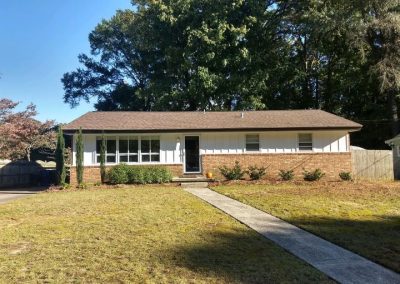 Brick and white board-and-batten ranch home with a new brown architectural shingle roof.