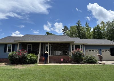 Ranch home with a stone-front porch and attached garage under a new gray shingle roof.