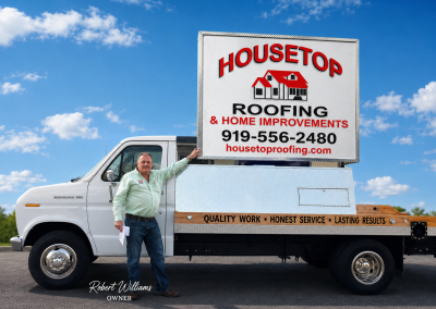 Housetop Roofing owner Robert Williams standing beside the company sign truck.