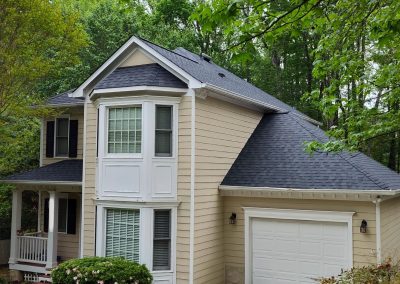 Tan two-story home in Apex, NC with a new gray architectural shingle roof over the bay window and garage.
