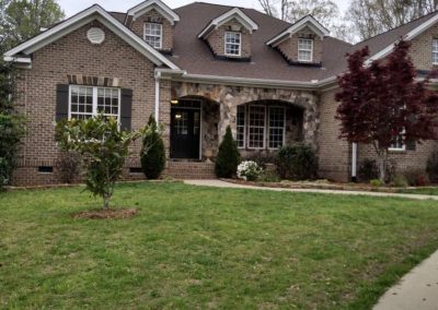 Brick and stone home in Wake Forest, NC with three dormers and a new brown architectural shingle roof.