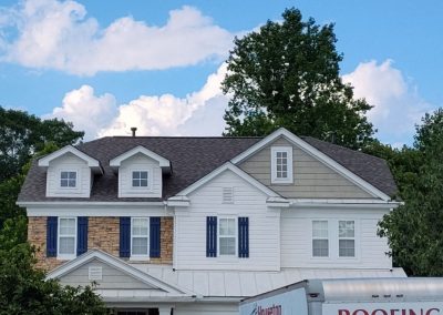 Two-story home with a new gray shingle roof, metal porch roof, and Housetop Roofing box truck in the driveway.
