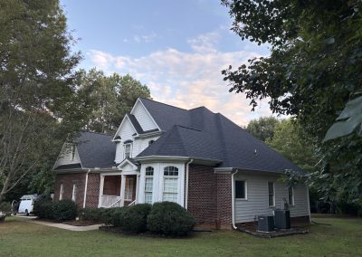 Brick and siding two-story home with bay windows and a new dark architectural shingle roof.
