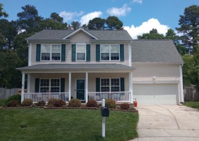 Two-story vinyl-sided home with green shutters, a front porch, and a new gray architectural shingle roof.